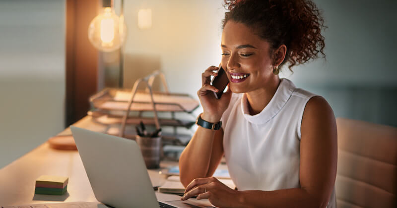 Smiling young woman looking up from her laptop